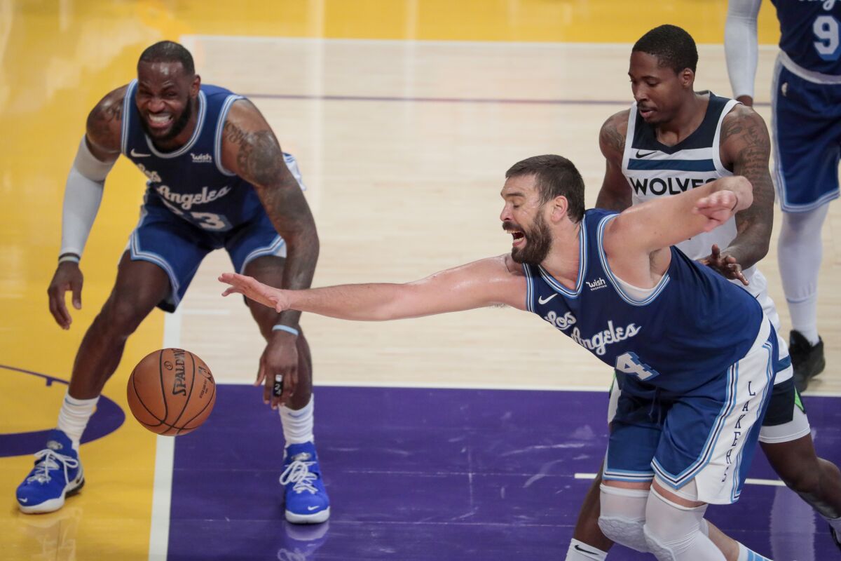 Lakers center Marc Gasol reaches for a loose ball while LeBron James and a Timberwolves player stand nearby.