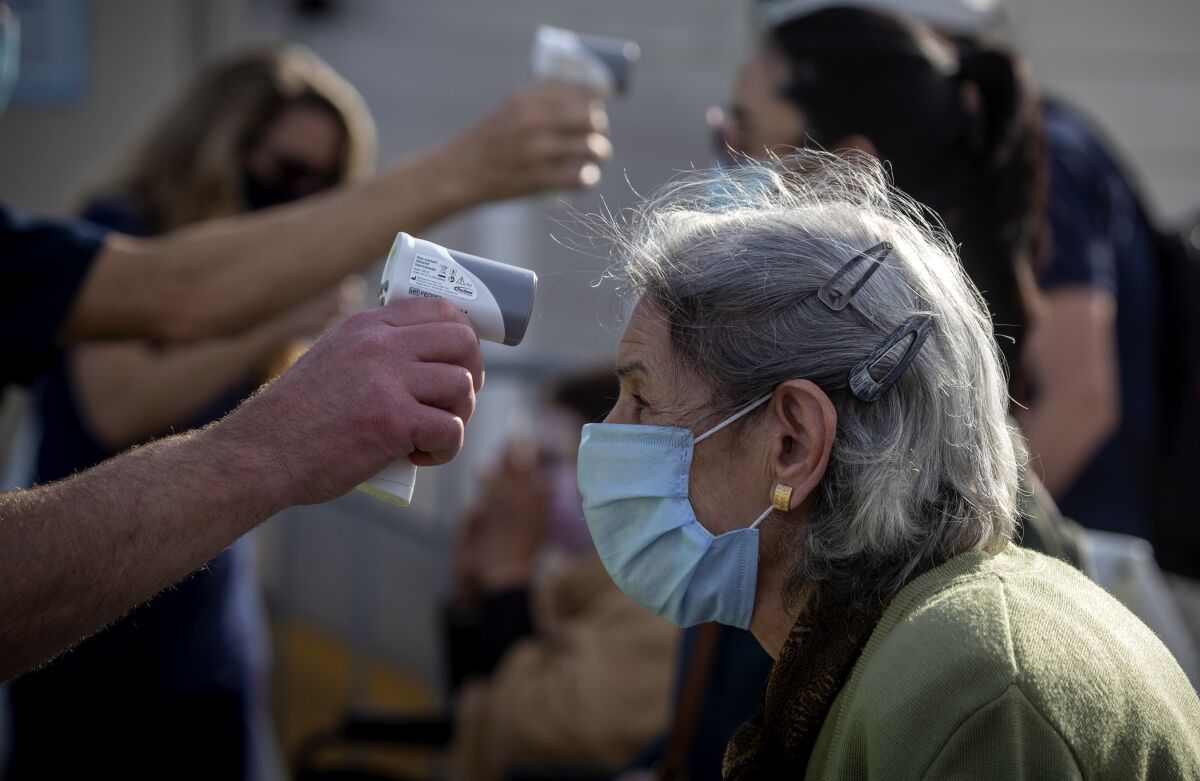 A resident has her temperature taken at Orange County's first large-scale vaccination site, at Disneyland, on Wednesday.