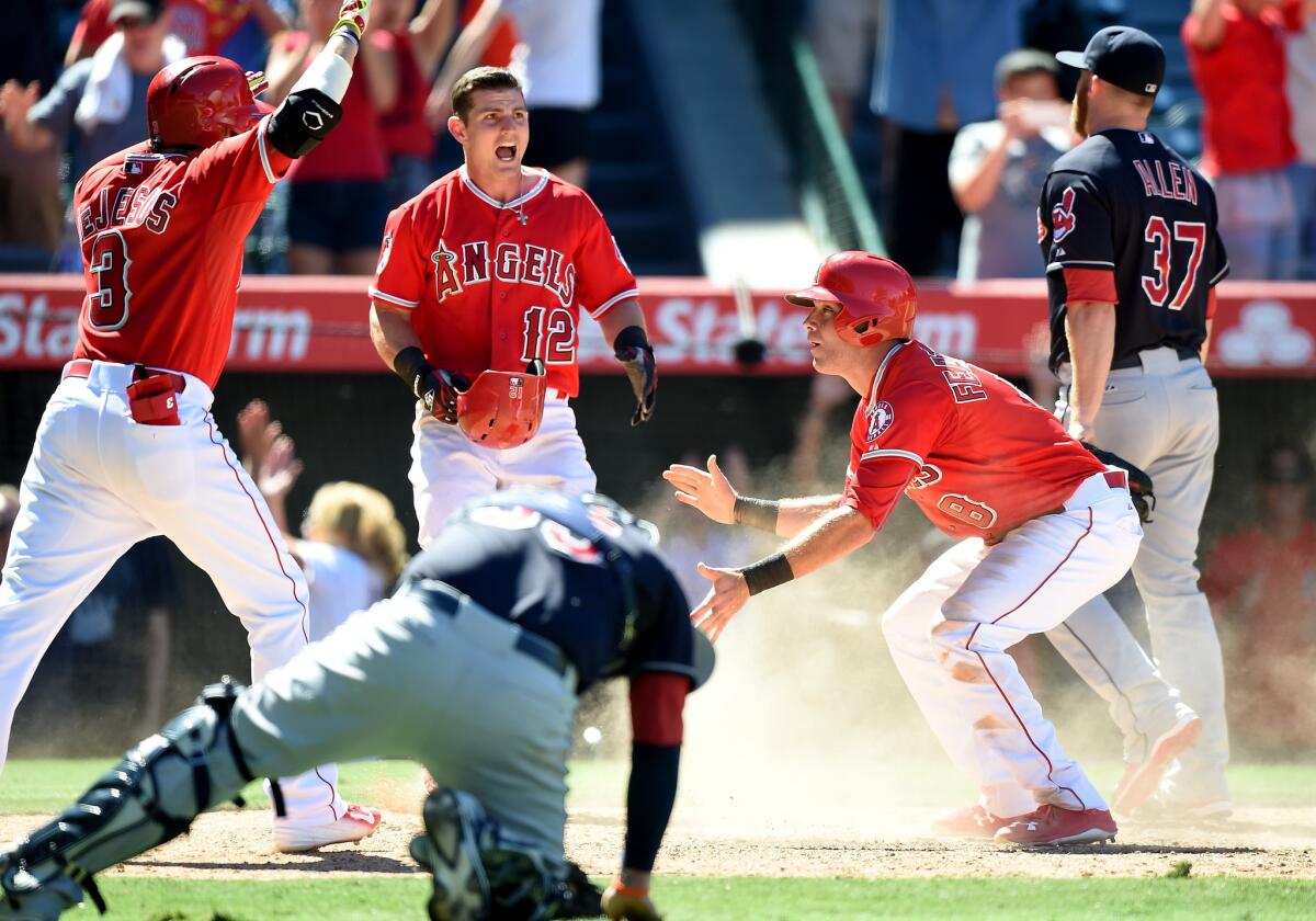 Angels pinch runner Taylor Featherston (8) reacts after scoring the winning run on a wild pitch by Indians closer Cody Allen as teammates David DeJesus (3) and Johnny Giavotella (12) celebrate the 4-3 win.