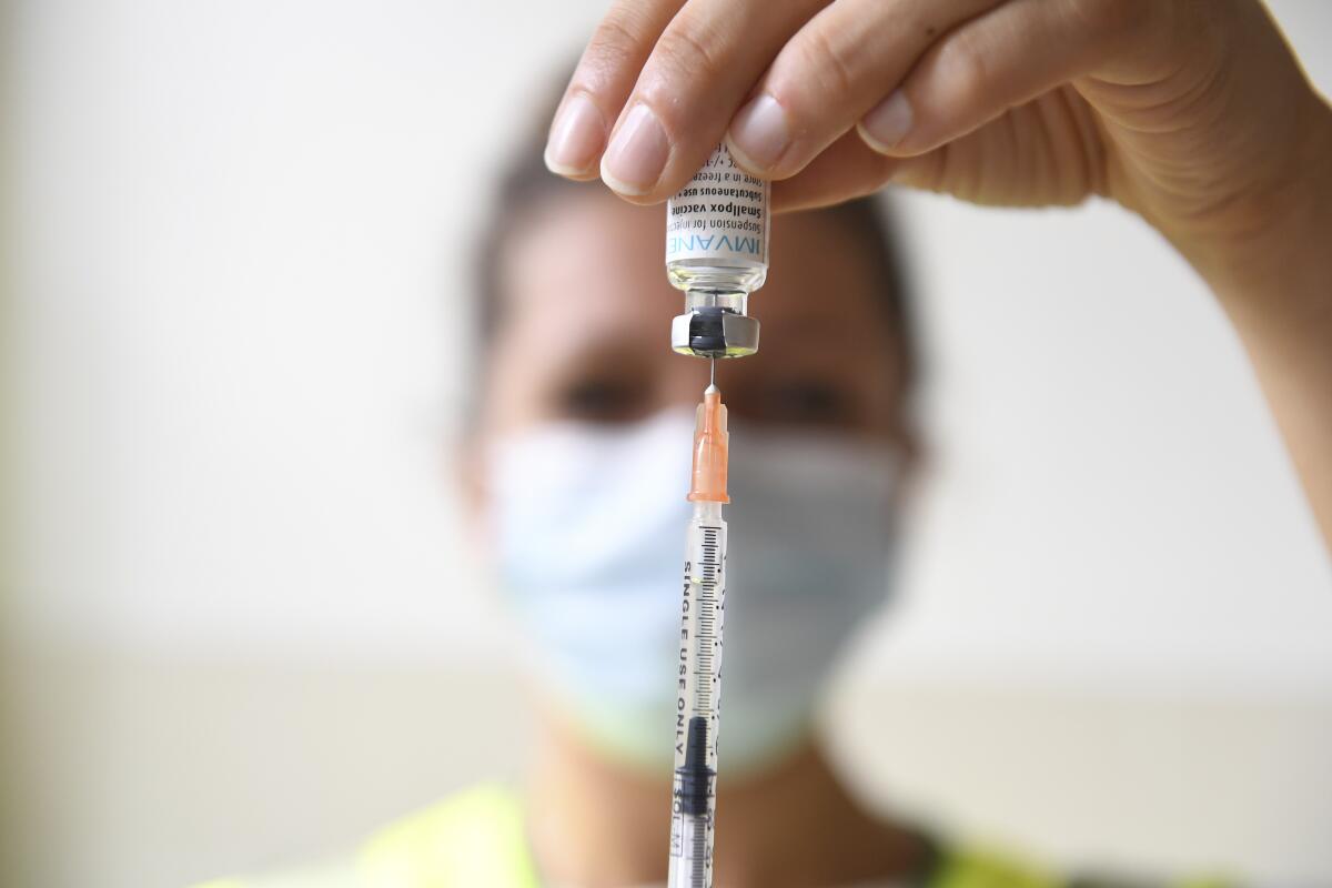 A needle is inserted into a bottle of monkeypox vaccine.