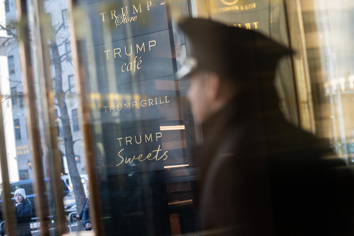 A person walks past the glass windows of Trump Tower