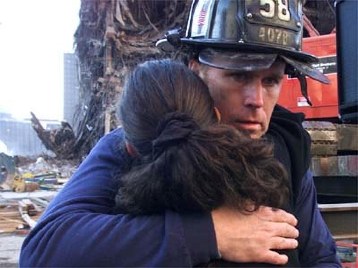 New York firefighter Gary McNulty comforts a mourner. The 5,000 seats provided weren't enough for mourners who attended the memorial service held at the site of the World Trade Center attack.
