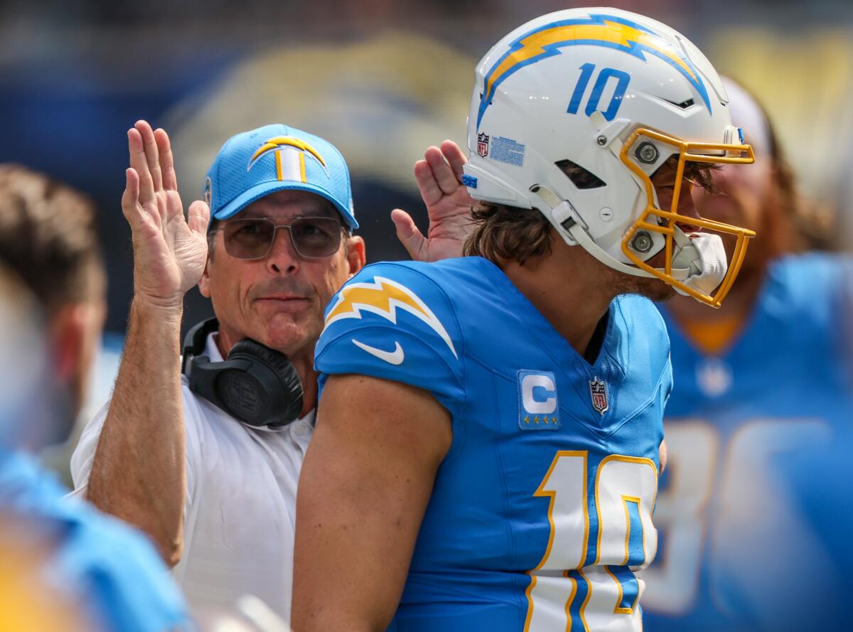 Chargers coach Jim Harbaugh slaps quarterback Justin Herbert on the back before a game.