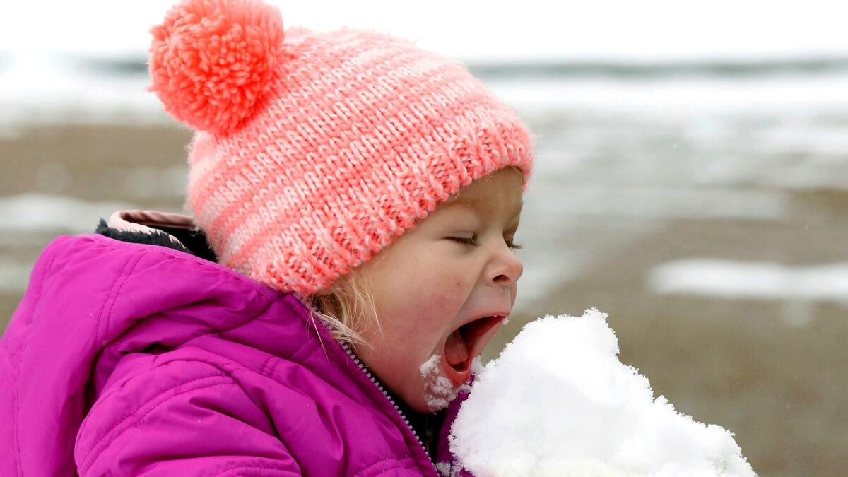 Emmaline Dendinger enjoys a bite of snow in her Jackson, Miss., neighborhood on Friday.