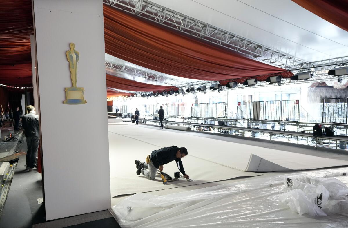 Un trabajador engrapa una alfombra durante los preparativos para la 95a edición de los Premios de la Academia