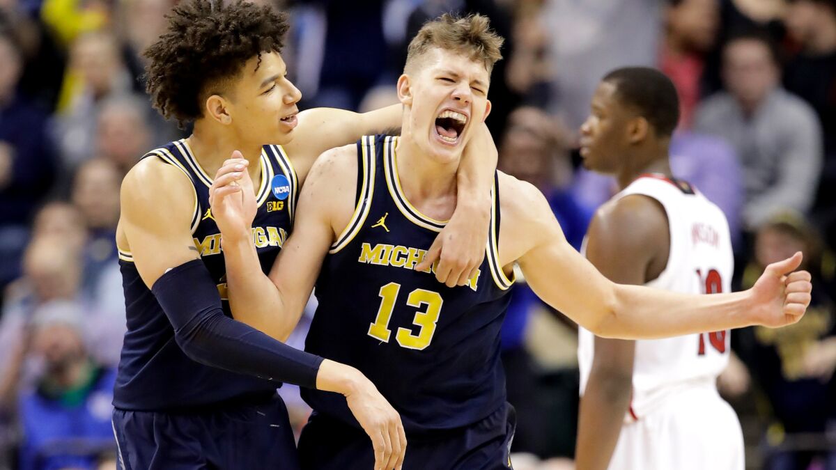 Michigan forward Moe Wagner (13) celebrates with teammate D.J. Wilson after scoring against Louisville in the second half Sunday.
