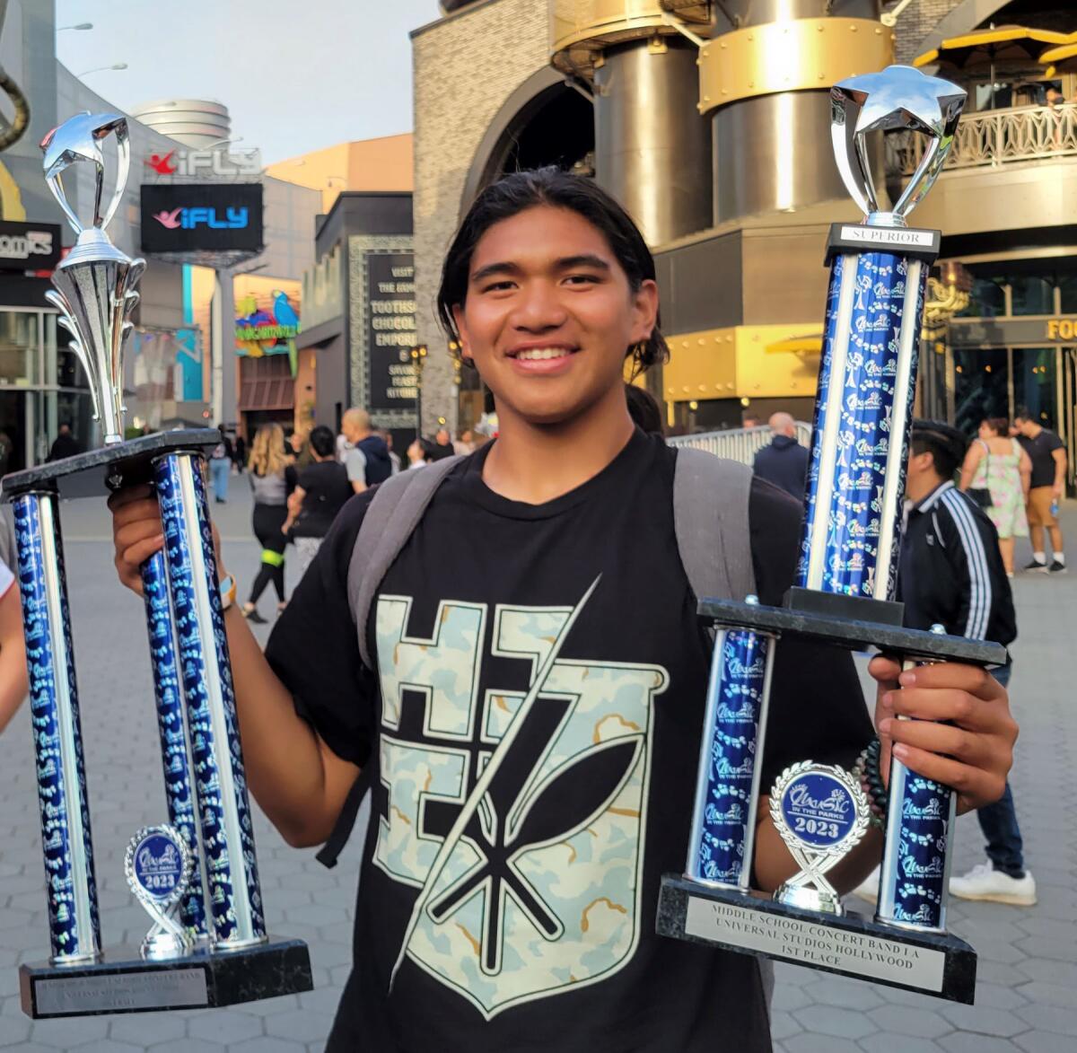 Cash K. Kalauli-Martin holding the school’s first-place trophies after winning the “Music in the Parks competition”