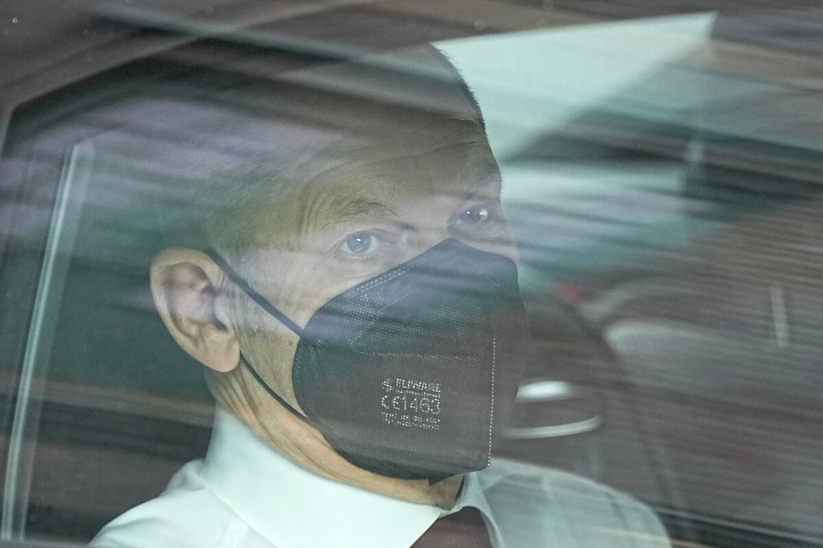 Olaf Scholz in a face mask looks out a vehicle window