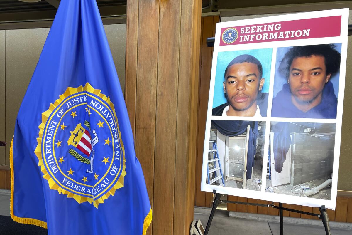 An FBI flag next to a poster reading "Seeking information" with photos of a man and a makeshift cell