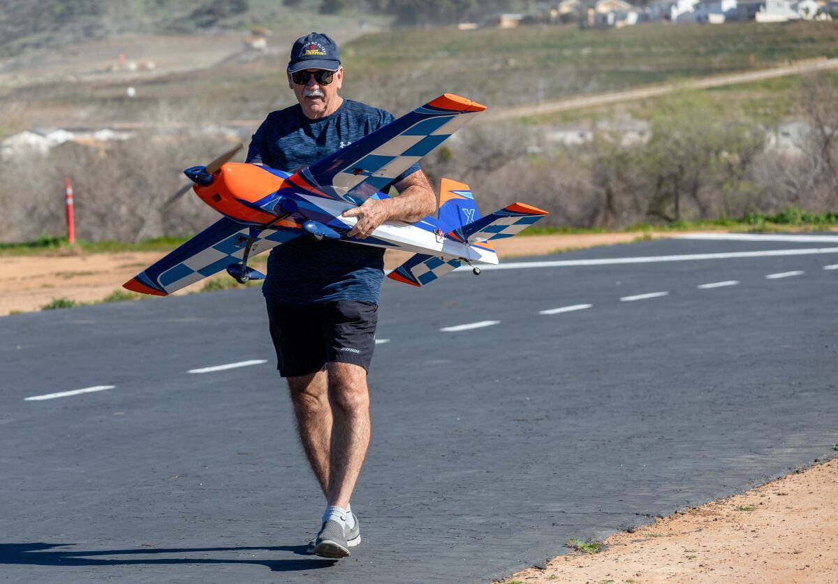 Palomar RC Flyers club member Steve Gebler carries a remote-control plane to the runway at Johnson Field in Fallbrook.