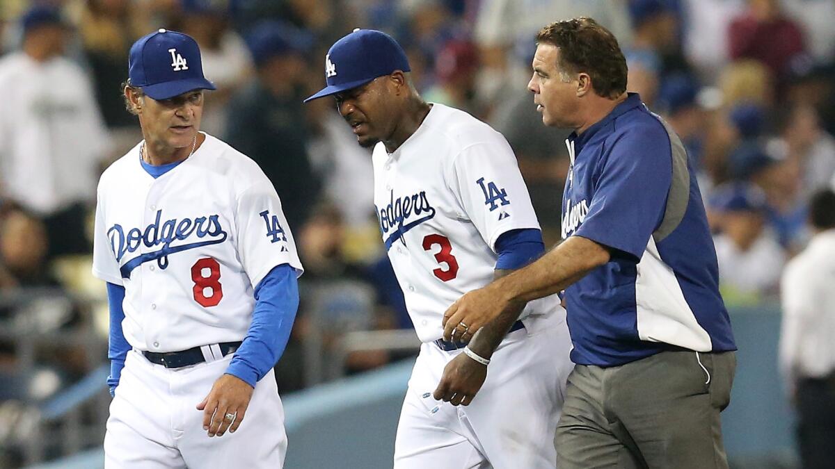 Dodgers left fielder Carl Crawford, center, walks off the field with Manager Don Mattingly and trainer Stan Conte after suffering an injury while chasing down a ball during the eighth inning of the team's 6-3 win over the Cincinnati Reds on Tuesday.