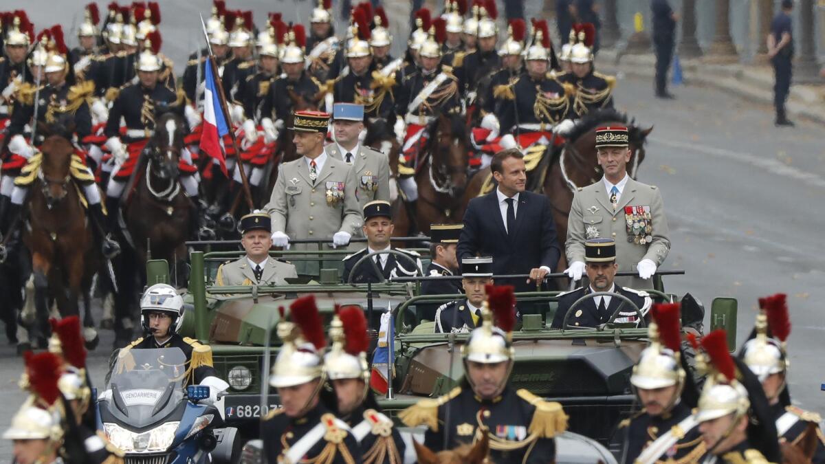 France's President Emmanuel Macron and Chief of Staff of the French Army General Francois Lecointre stand in the command car as they drive down the Champs-Elysees during the Bastille Day parade in Paris on Sunday.