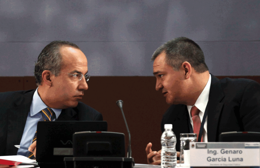 El entonces presidente de México, Felipe Calderón, habla con su secretario de Seguridad Pública, Genaro García Luna, durante una mesa redonda sobre seguridad, en agosto de 2010.