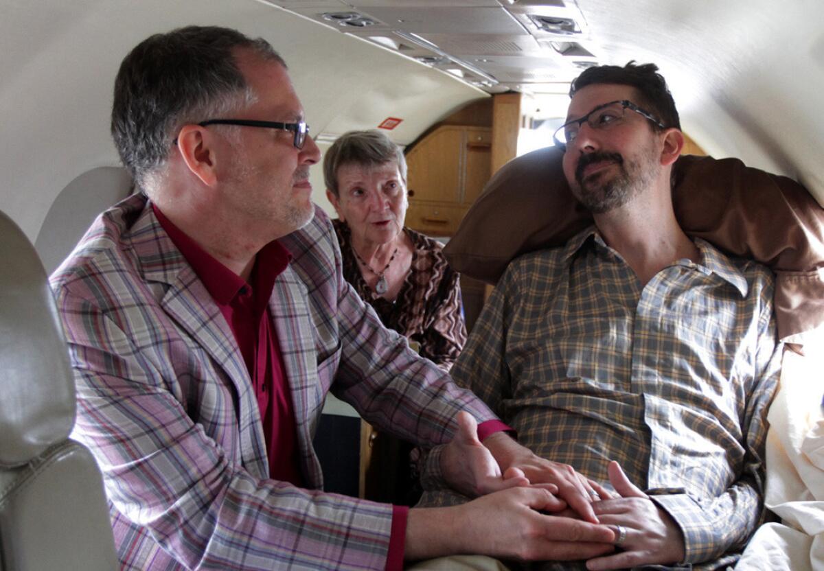 Officiant Paulette Roberts, center, marries James Obergefell, left, and John Arthur, who is dying of Lou Gehrig's disease, aboard a plane at Baltimore/Washington International Thurgood Marshall Airport in Maryland. The federal judge who ruled in their favor and recognized their marriage has made a similar ruling in another case.