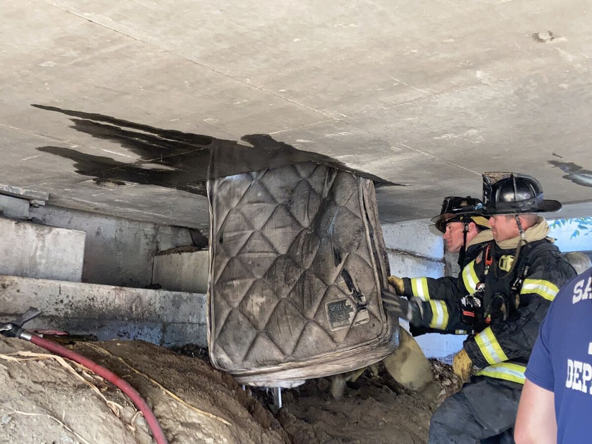 Sacramento firefighters remove a mattress from underneath an overpass on Highway 160.