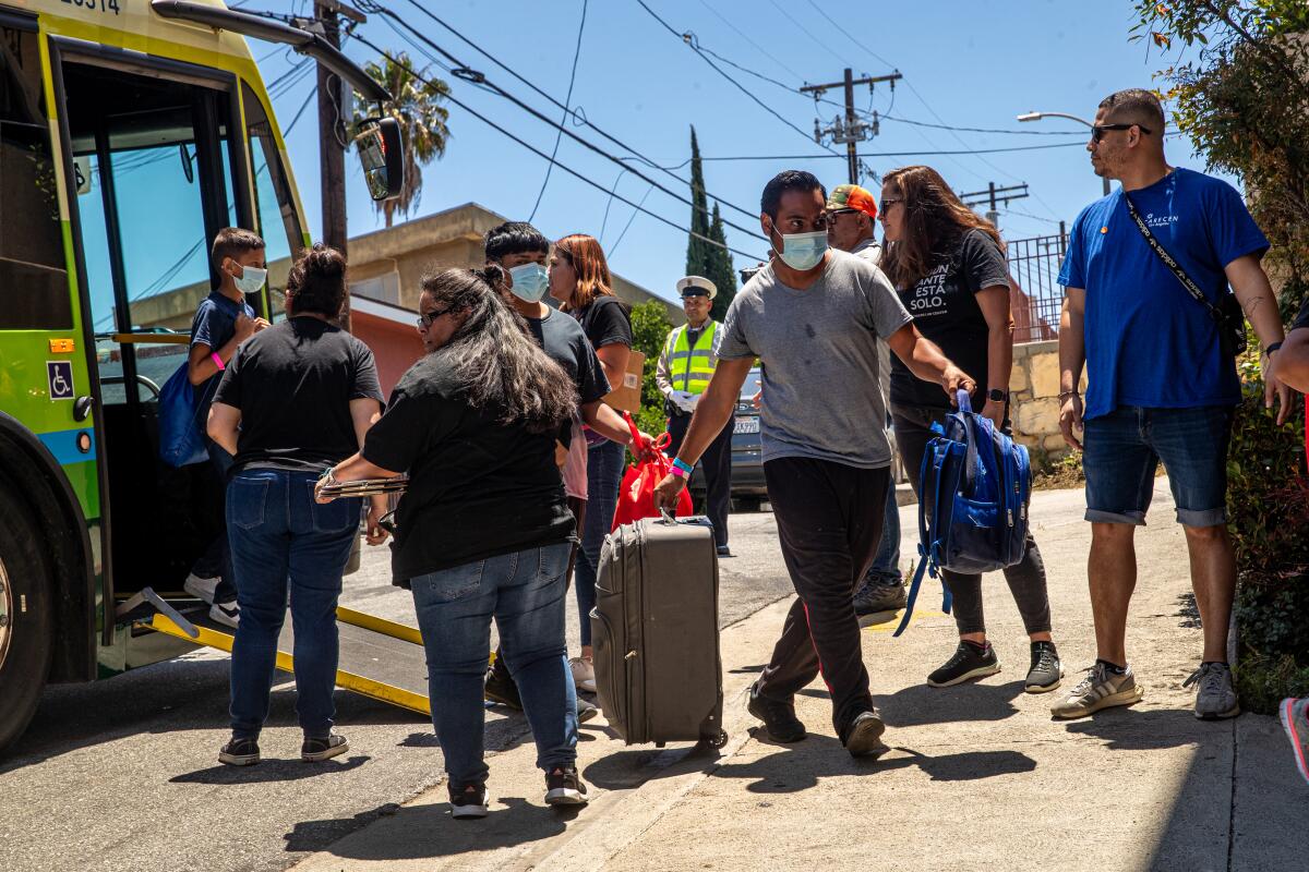 Several people standing near a bus as others leave with luggage