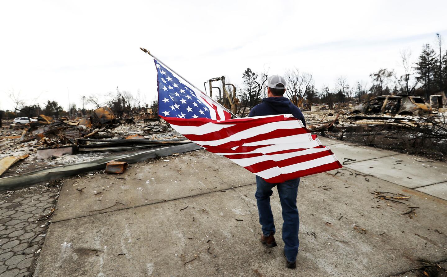 Jason Miller, 45, prepares to plant an American flag on the charred remains of his house as residents of Coffey Park, devastated by the Tubbs fire, return home on Oct. 20.