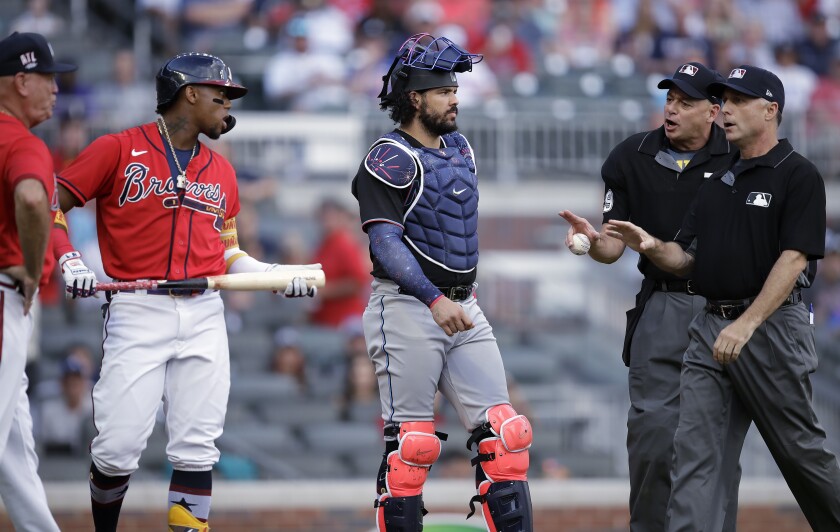 Umpires speak with Atlanta Braves' Ronald Acuna Jr., holding bat, and manager Brian Snitker, left, as Miami Marlins catcher Jorge Alfaro, center, looks on after Acuna was hit by the first pitch thrown by Marlins' Pablo Lopez in the first inning of a baseball game Friday, July 2, 2021, in Atlanta. (AP Photo/Ben Margot)