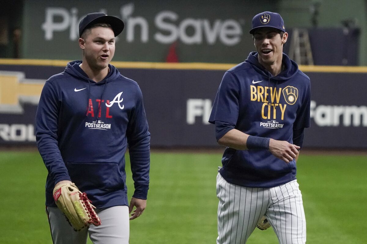 Milwaukee Brewers' Christian Yelich talks to Atlanta Braves' Joc Pederson at a practice for the Game 1 of the NLDS baseball game Thursday, Oct. 7, 2021, in Milwaukee. The Braves plays the Milwaukee Brewers in Game 1 on Friday, Oct. 8, 2021. (AP Photo/Morry Gash)