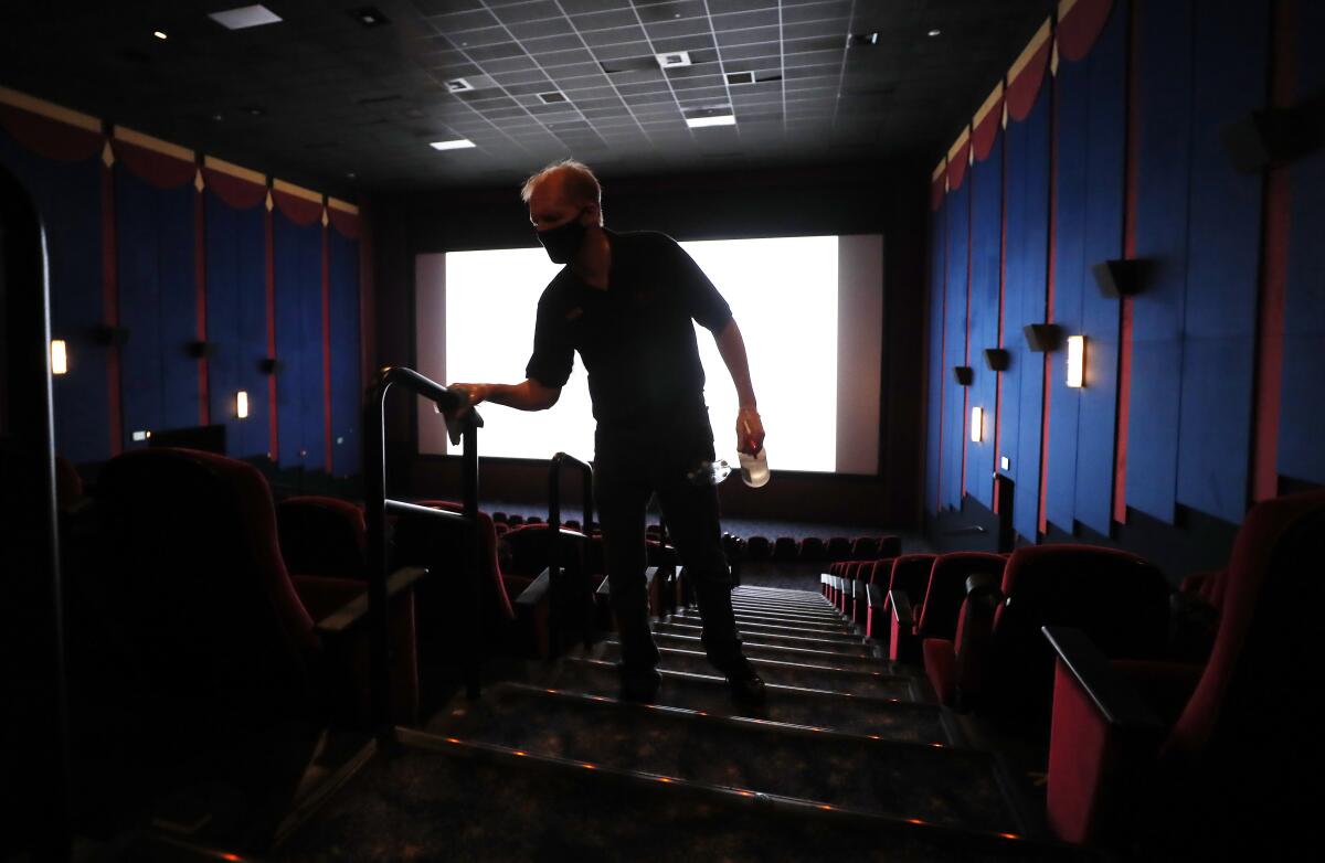A worker cleans a La Mesa movie theater on the first day of being open since the COVID-19 pandemic shutdown. 