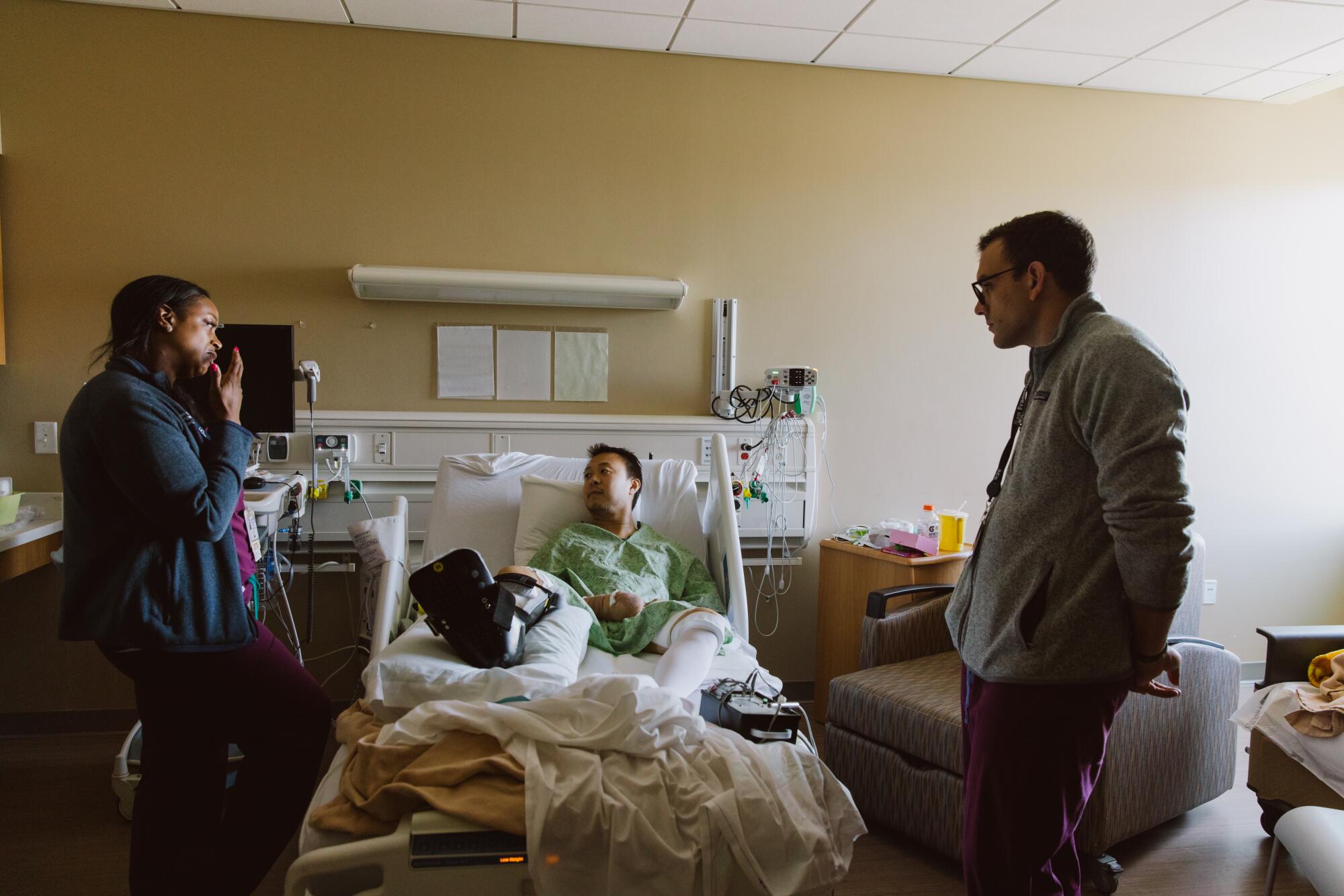 Two doctors stand around the bedside of a patient.