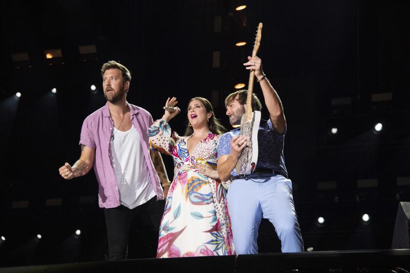 Two men flank a woman as they perform onstage