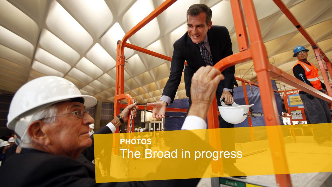 Los Angeles Mayor Eric Garcetti, right, offers a hand to philanthropist Eli Broad as they climb onto a lift in the third floor gallery.