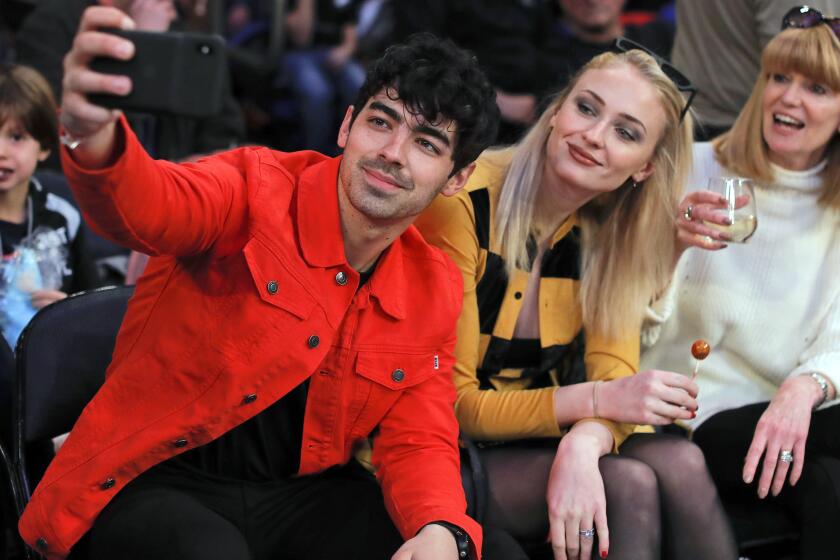 FILE Musician Joe Jonas, left, takes a selfie with actress Sophie Turner during a break in play of an NBA basketball game between the New York Knicks and the Sacramento Kings, Saturday, March 9, 2019, in New York. Turner sued her estranged pop star husband Jonas on Thursday, Sept. 21, 2023, to force him to turn over the passports of the couple's two young daughters so she can take them to England. (AP Photo/Julie Jacobson, File)