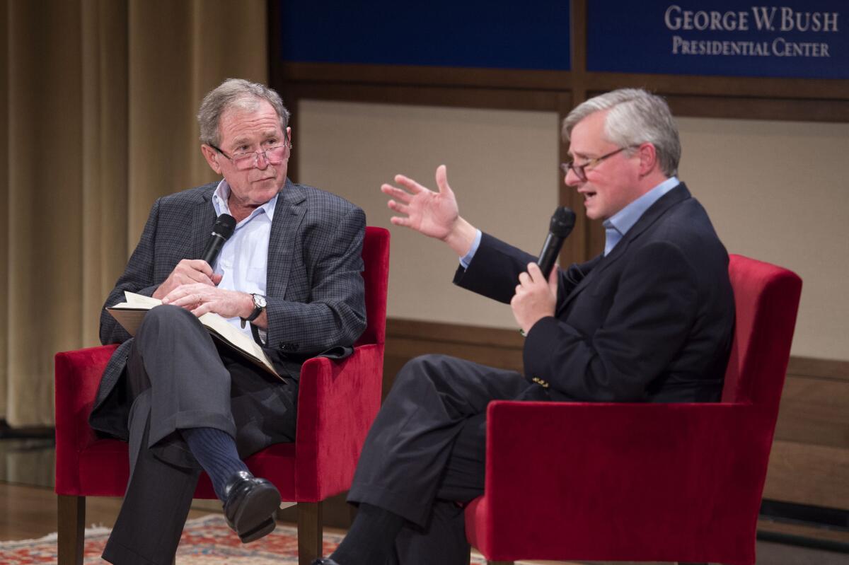 Former President George W. Bush, left, listens to author Jon Meacham talk about his biography of Bush's father, former President George H.W. Bush.