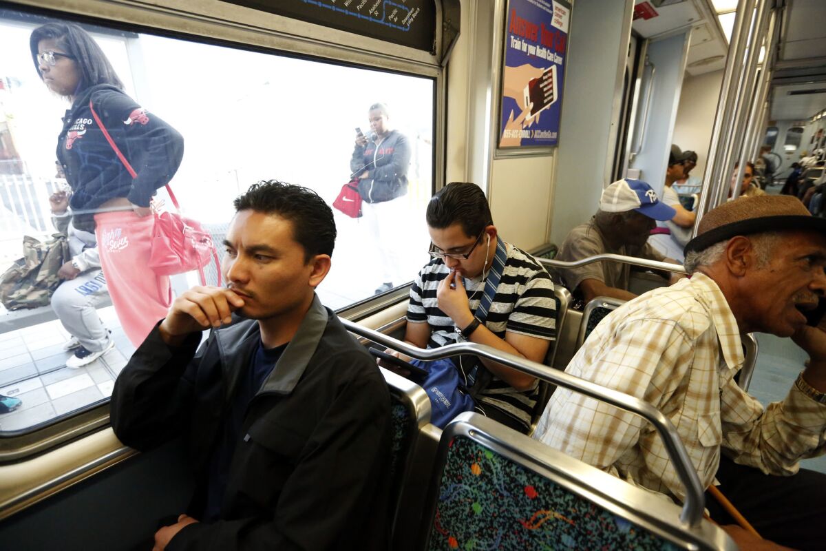 Phal Sok, 35, left, rides the Metro Blue Line train in Los Angeles to visit with his brother in Long Beach. (Genaro Molina / Los Angeles Times)