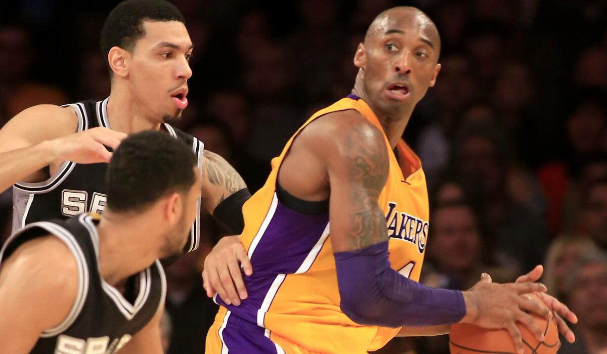 Lakers guard Kobe Bryant looks to pass against the defense of Spurs guards Danny Green and Cory Joseph in the first half.