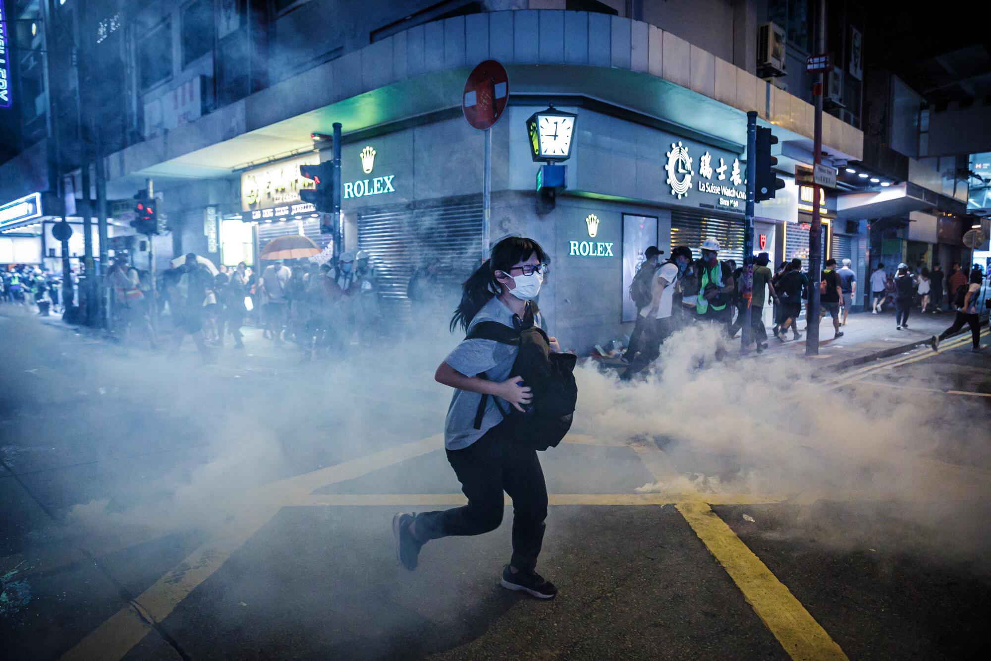 A woman runs through tear gas on a city street 