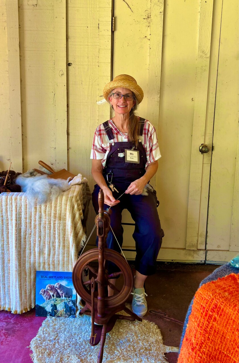 Kristin Osborn, President and Market Coordinator of the Poway Arts and Crafts Guild, spins yarn at the craft market.