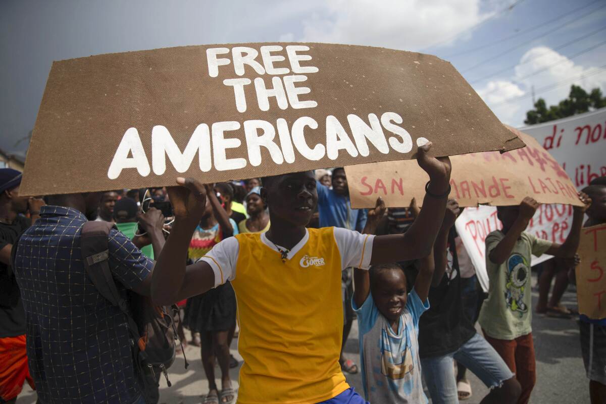 A protester holds a sign reading "Free the Americans" near the missionaries' headquarters in Haiti.