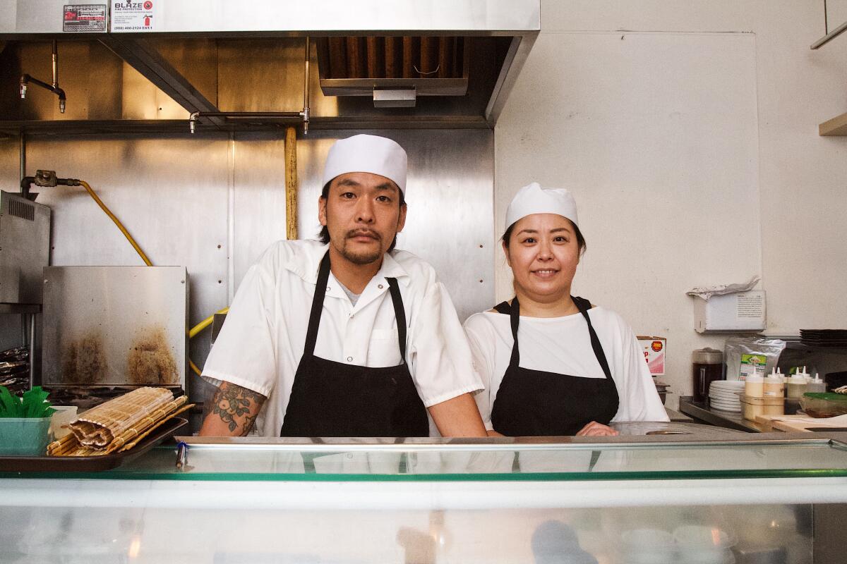 Murakami Sushi chef Taro Sato and owner Tomoko Bright stand behind the sushi counter of the Melros restaurant