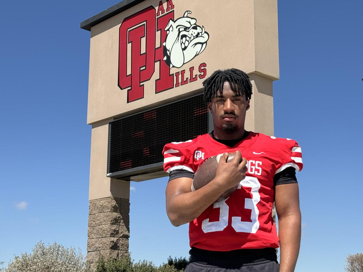 Running back Karson Cox of Oak Hills High poses with a football tucked under his right arm. 