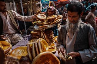 A man counts his Afghan currency before paying for bread in an open air street market/