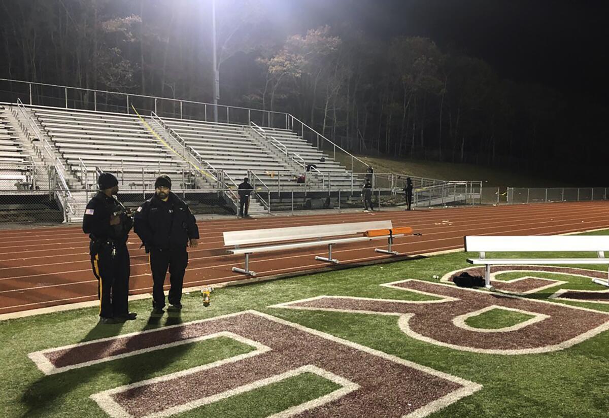Police stand near empty grandstands at a high school in New Jersey.