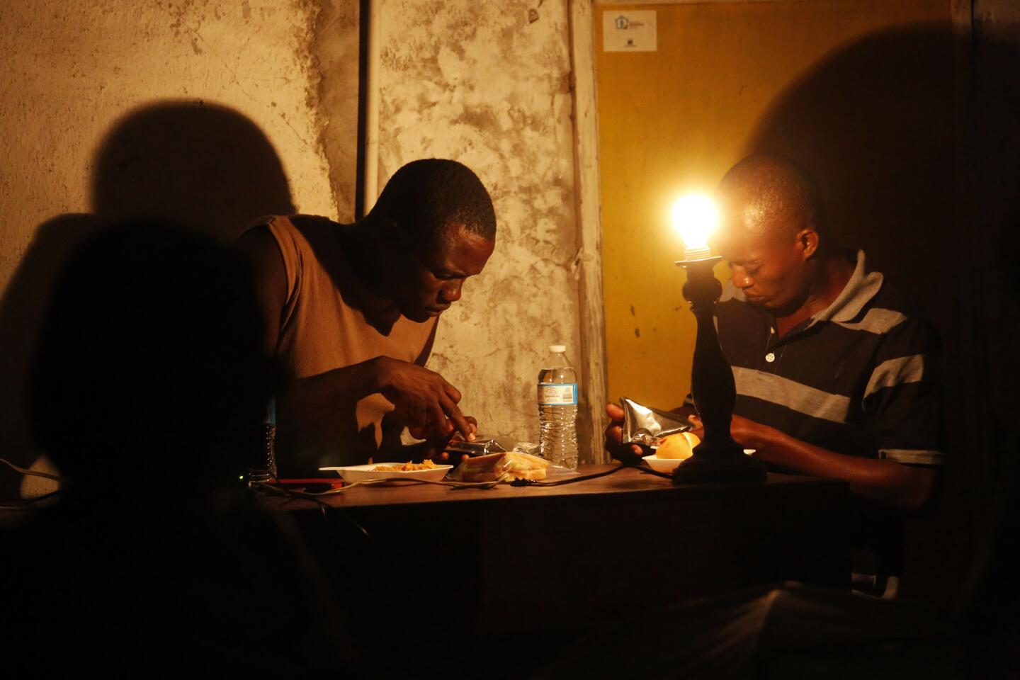 Haitian and African migrants check their phones while staying at a small tent city operated by Movimiento Juventus 2000.