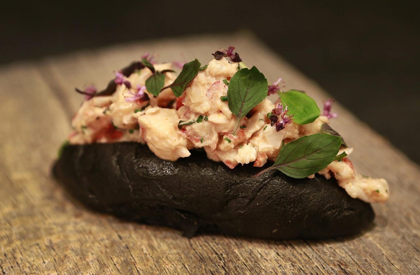 A lobster roll with green curry and Thai basil on a charcoal-infused bun at Hinoki & the Bird, a restaurant at the base of a Century City condo tower.