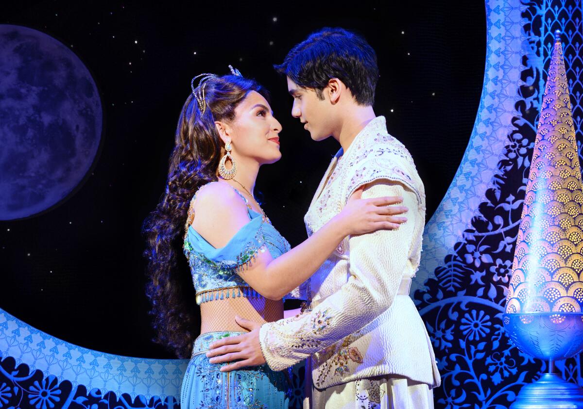 Actors playing Jasmine and Aladdin in the musical "Aladdin" embrace.