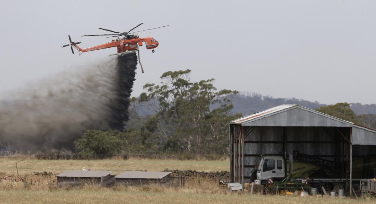 A helicopter drops water to hold back a wildfire from the hamlet of Claredon in Victoria, Australia.