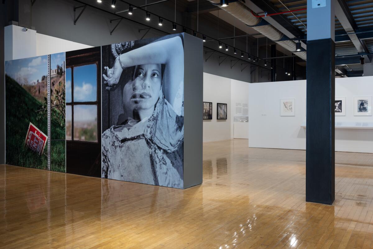 Photographs, including an oversize shot of a girl, her arm over her head, on display in a museum