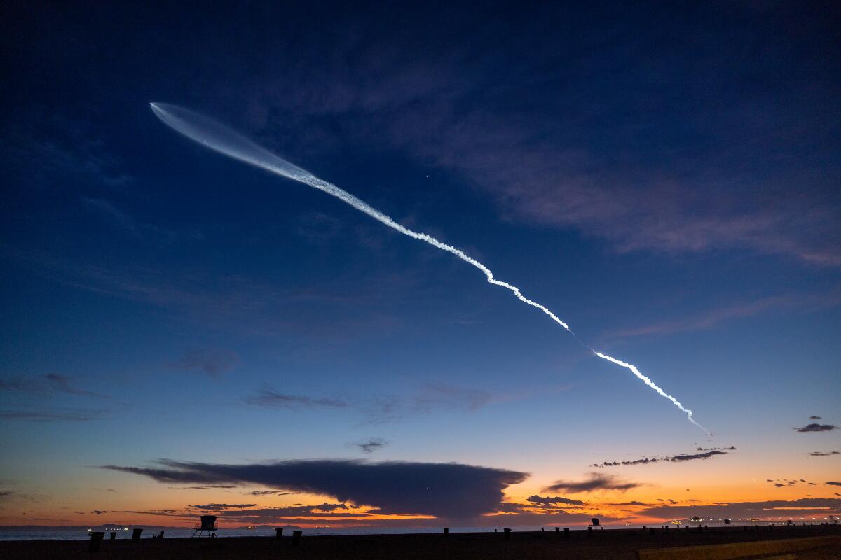 The launch of SpaceX Falcon 9 rocket, leaving contrails across the sky at dusk.