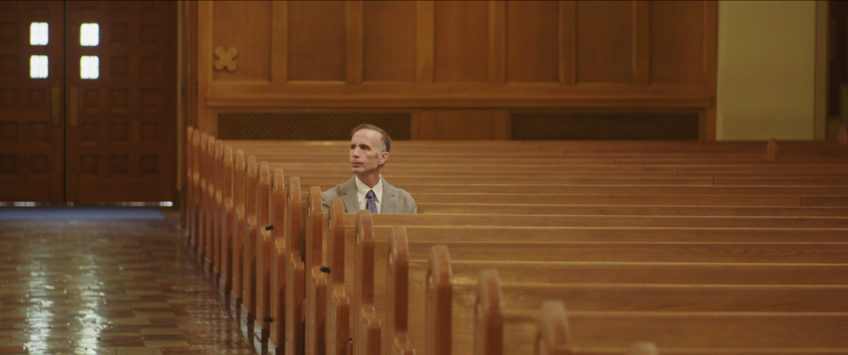 Michael Sandridge sits alone in a pew in an empty church in a scene from ‘Procession.’ 