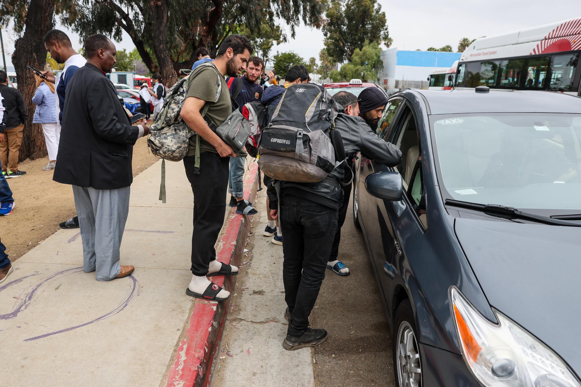   边境巡逻人员将移民送至艾里斯大道站，移民们与出租车司机协商车费。 
