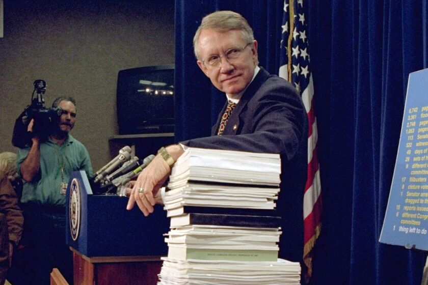 FILE - Sen. Harry Reid, D-Nev., leans on a stack of documents pertaining to campaign finance reform during a Capitol Hill news conference on Dec. 3, 1996, where the Democratic leadership for the 105th Congress was announced. Reid, the former Senate majority leader and Nevada’s longest-serving member of Congress, has died. He was 82. (AP Photo/Dennis Cook, File)