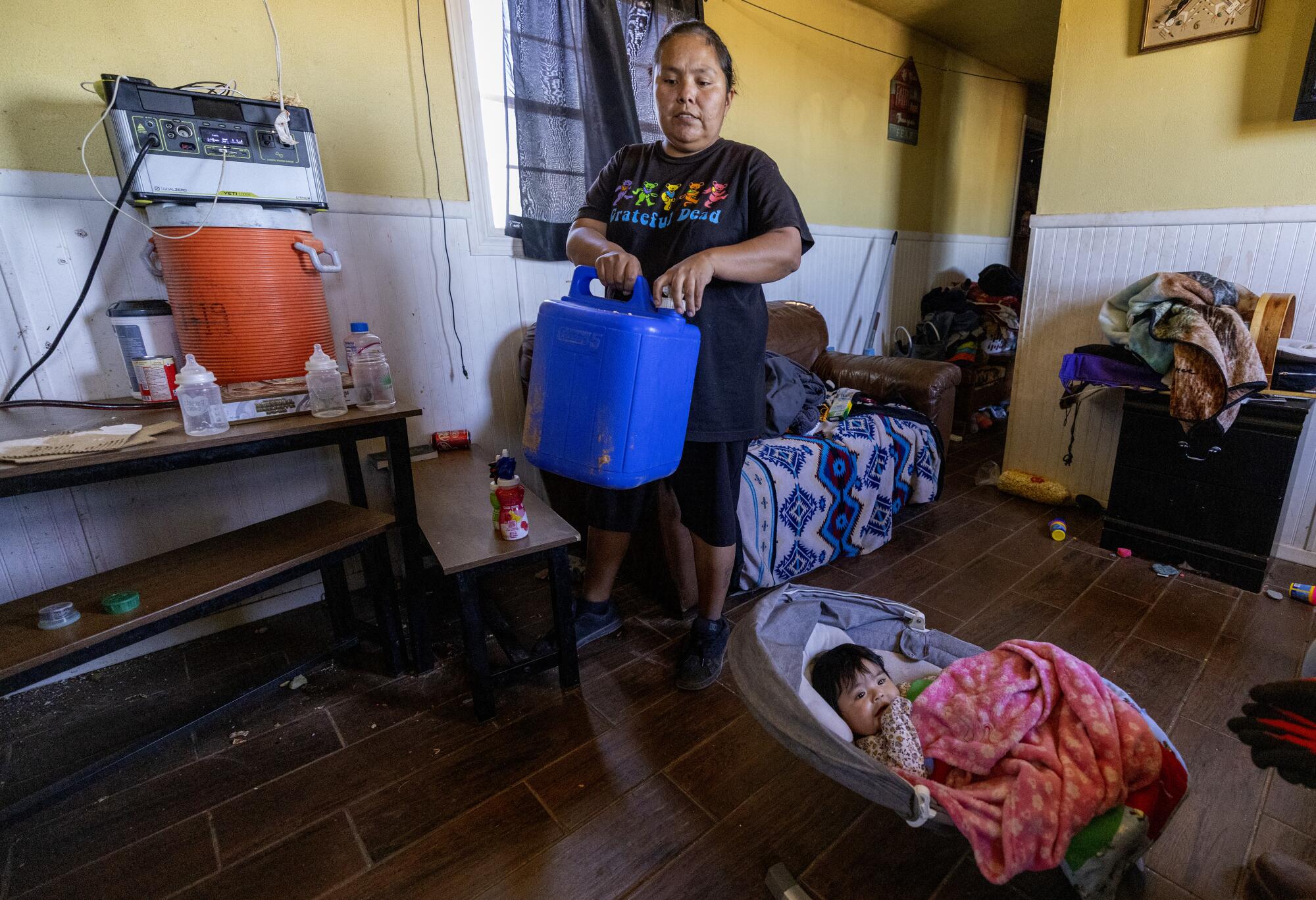 Gilarya Begaye carries a five gallon water jug she no longer needs inside her Navajo Nation home.