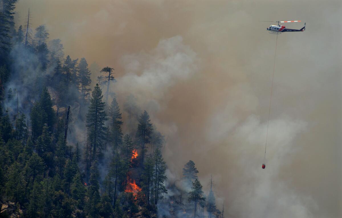 A firefighting helicopter drops water on the Slide fire in Oak Creek Canyon in Sedona, Ariz., on May 22.