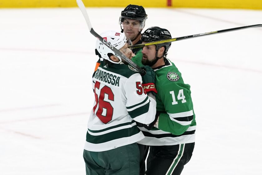 An official breaks up an argument between Minnesota Wild's Joseph Cramarossa (56) and Dallas Stars' Jamie Benn (14) during the second period of a preseason NHL hockey game in Dallas, Thursday, Sept. 29, 2022. (AP Photo/Tony Gutierrez)